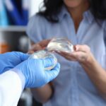 Woman inspecting two different breast implants with a doctor